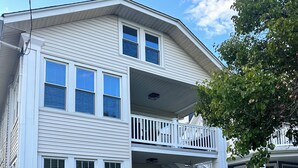 A multi-story building with white siding, a front porch, and a staircase leading to the second floor. - 3 Bedroom House, 1 Block from Beach and Boardwalk (Ocean City)