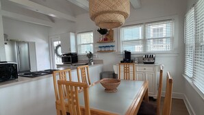A modern kitchen with white cabinets, a dining area with wooden chairs, a large island, and a hanging light fixture. - 3 Bedroom House, 1 Block from Beach and Boardwalk (Ocean City)