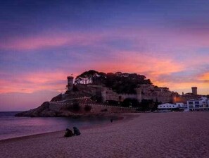 Un paysage côtier avec un fort historique perché sur une colline, dominant la plage.