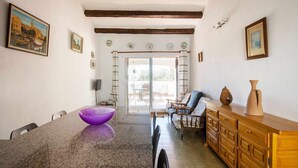 A dining area with a granite table, chairs, and a purple bowl. There is a wooden cabinet with vases and a painting on the wall. - Casa Tossa – Pool, Parking & Terrace (27) (Tossa De Mar)