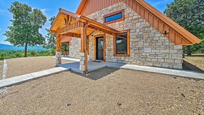 Una casa moderna con fachada de piedra, un porche de madera y vistas al paisaje.