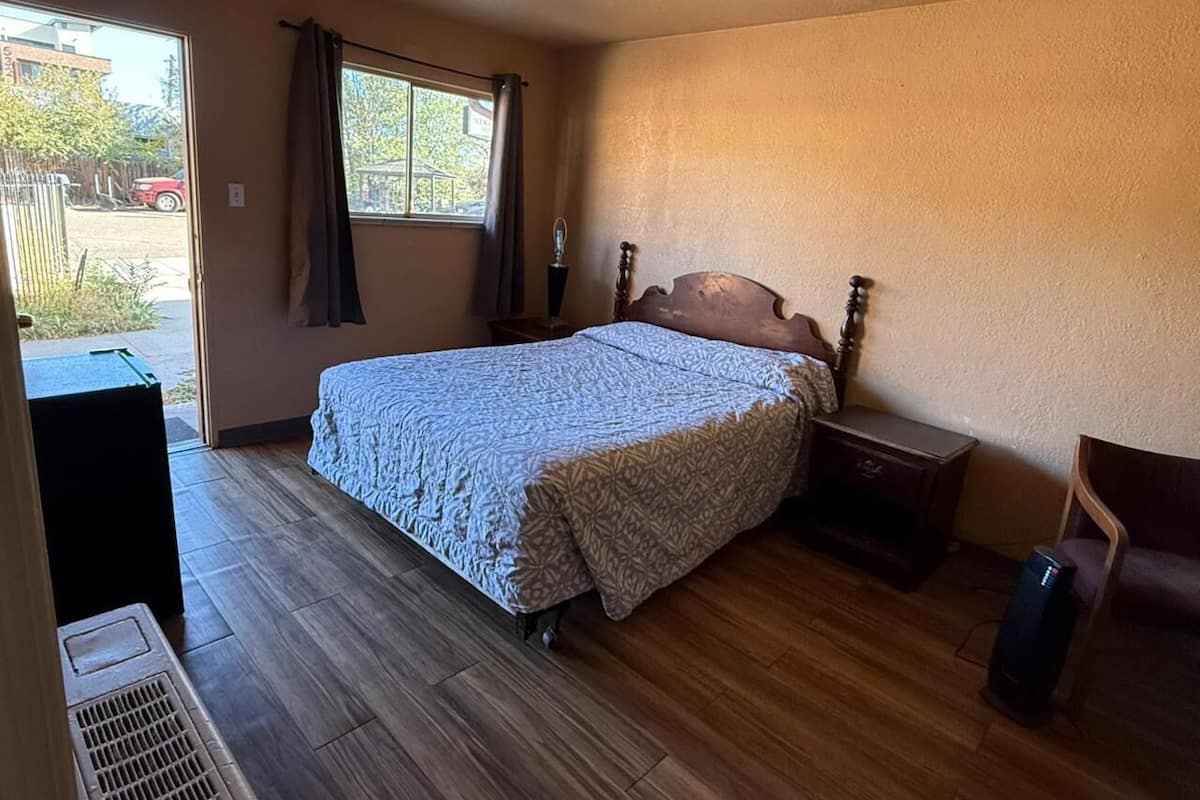 A room with a bed, a nightstand, a chair, and a window.