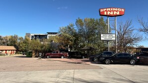 A Springs Inn sign with amenities including free WiFi, free cable, and a coin laundry. - Springs Inn by Capital O I 25 (Colorado Springs)