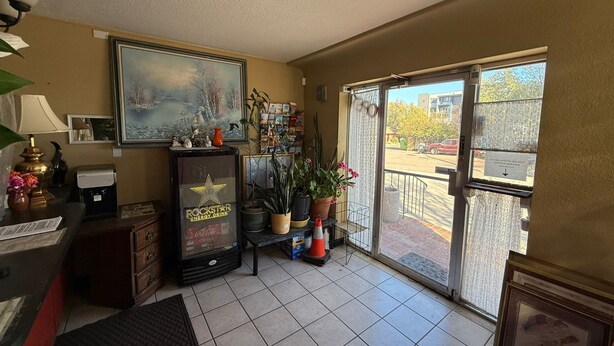 A room with a large window, a refrigerator, a painting, and various plants. - Springs Inn by Capital O I 25 (Colorado Springs)
