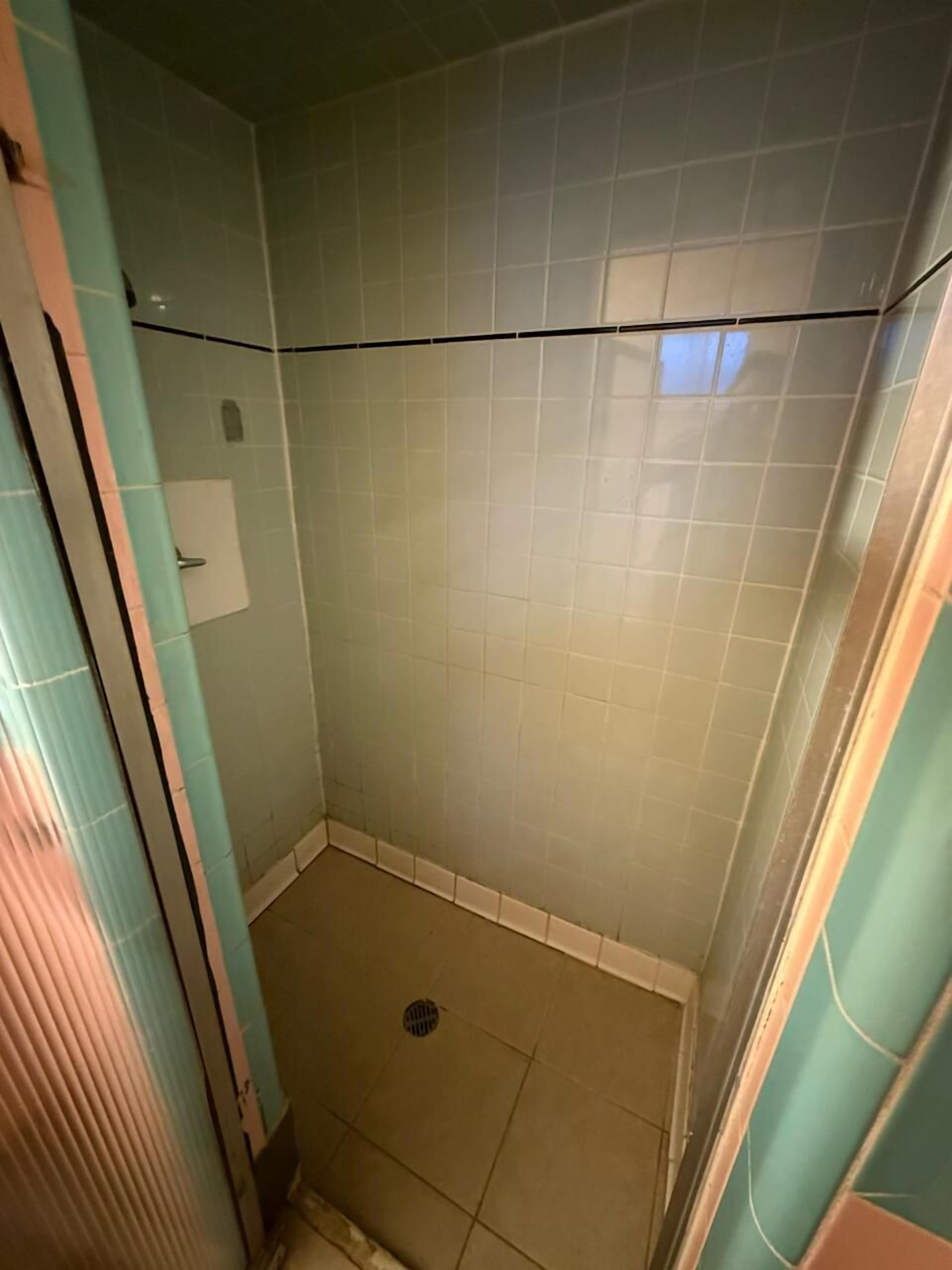 A small, tiled shower area with a drain in the center.