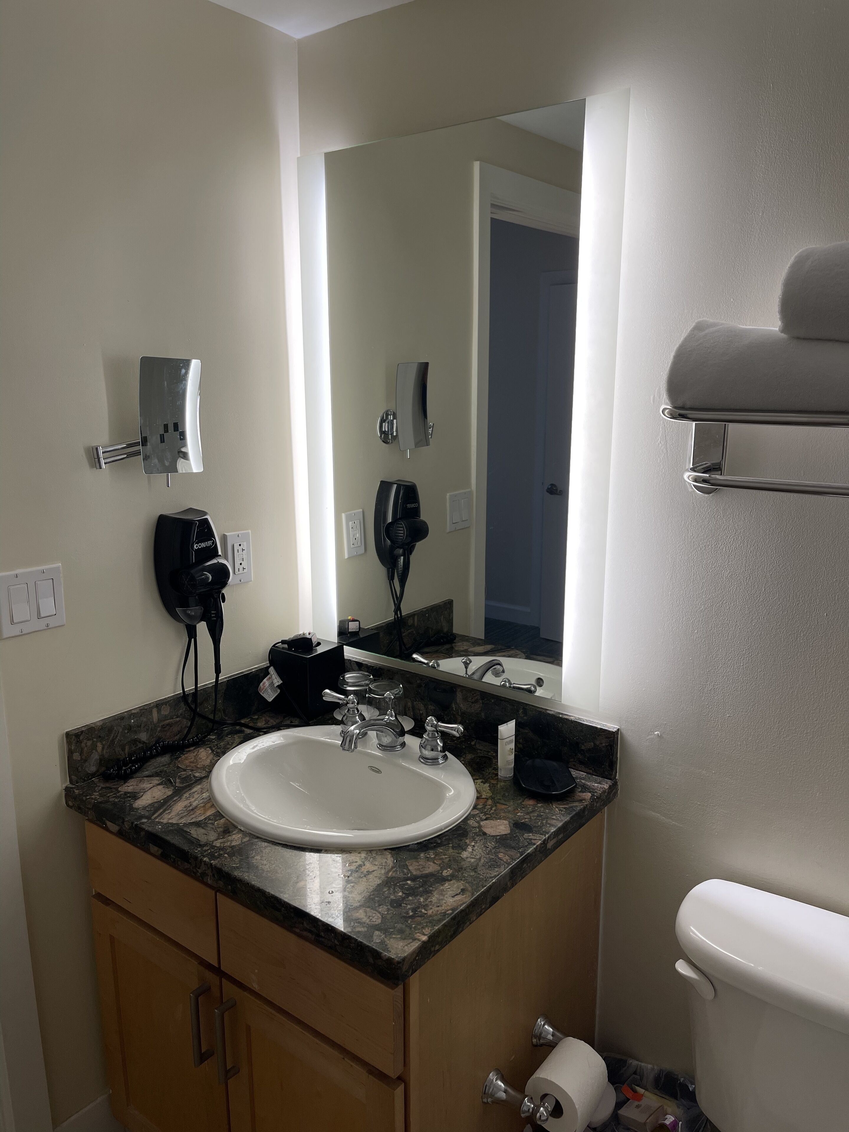 A bathroom with a sink, mirror, towel rack, and toilet.