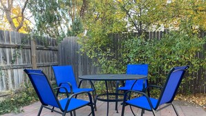 A patio with a round table and four blue chairs. - Historic Bluebell. Entire House. 2Br Cozy but spacious (Wheatland)