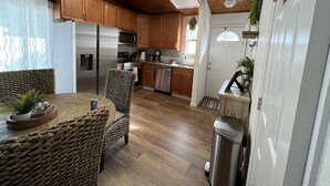 Une cuisine dotée de meubles en bois, d’appareils électroménagers en acier inoxydable et d’un coin repas avec des chaises en osier.