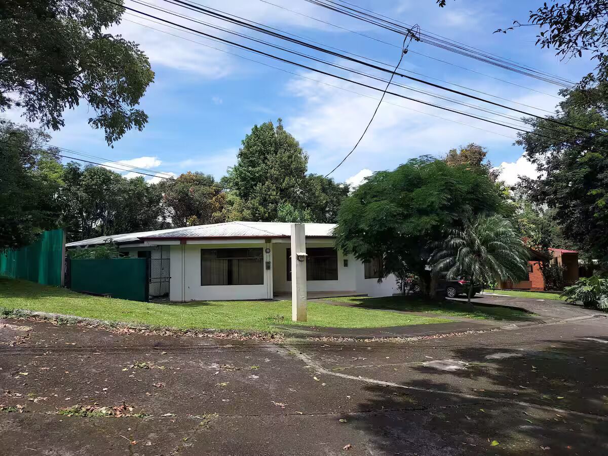 A single-story house with a white exterior, a front porch, and a small front yard.