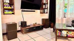 Een woonkamer met een flatscreen televisie aan de muur, omringd door boekenkasten vol boeken en dvd's. Aan weerszijden van de tv-standaard staan twee speakers.