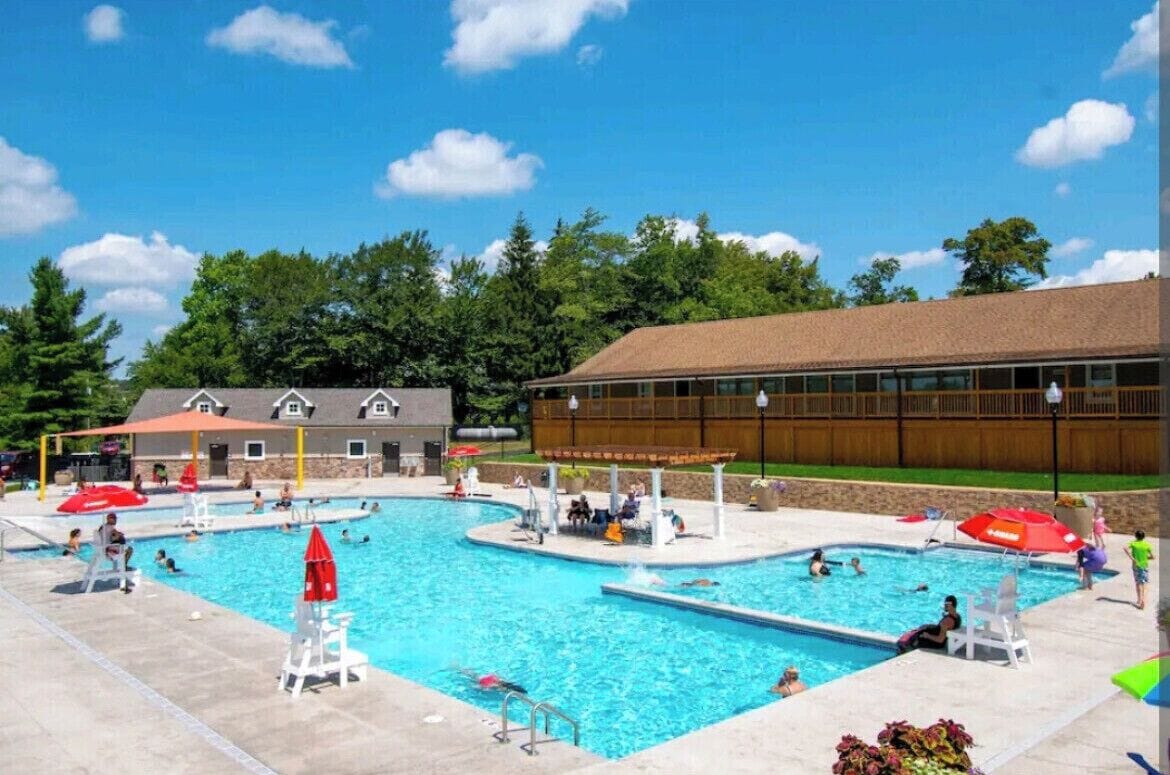 A swimming pool area with multiple pools, lounge chairs, and umbrellas.