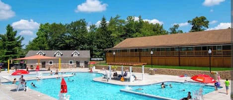 A swimming pool area with multiple pools, lounge chairs, and umbrellas.