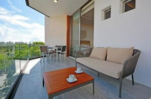 Un balcon moderne avec un canapé, des chaises et une table sur laquelle sont posées des tasses.