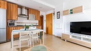 A modern kitchen with wooden cabinets, a microwave, and a dining area with a table and chairs. - A&n Levante Torre del Mar (Torre del Mar)