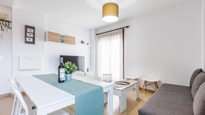 A modern living room with a sofa, a dining table with chairs, a TV, and a plant. - A&n Levante Torre del Mar (Torre del Mar)