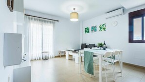 A modern, well-lit living area with a dining table, chairs, a sofa, and a TV. - A&n Levante Torre del Mar (Torre del Mar)