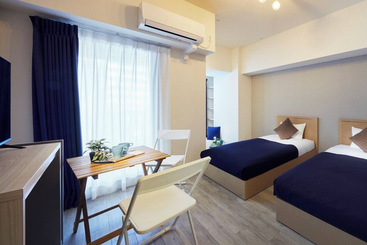 Une chambre d’hôtel avec deux lits, un bureau, une chaise, une télévision et un appareil de climatisation.