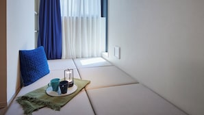 Un rincón acogedor con un banco acolchado, un cojín azul, una bandeja con dos tazas y un farol.