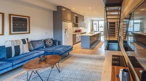 Relax in this open-plan living space featuring a kitchen area with an island and a cozy seating area with a sofa and rug.