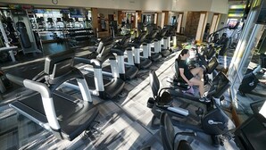 Ett gym med flera löpband, styrketräningsmaskiner och en vägg täckt med speglar.