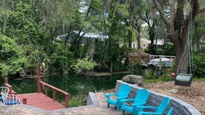 A patio with Adirondack chairs, a stone fire pit, and a pond. - Welcome to Let's Flamingle, located directly on Blue Cove just off of Rainbow River (Dunnellon)