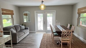 A dining area with a table and chairs, a sofa, a mirror, and a ceiling light fixture. - Welcome to Let's Flamingle, located directly on Blue Cove just off of Rainbow River (Dunnellon)
