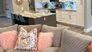 A modern kitchen with white cabinets, a central island, and a dining area with chairs. - Welcome to Let's Flamingle, located directly on Blue Cove just off of Rainbow River (Dunnellon)