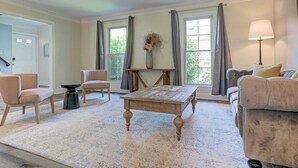 A living room with a large window, a coffee table, two armchairs, a sofa, and a lamp.