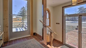 A staircase with wooden handrails and a glass door leading outside. - Renovated Historic Church Along Namekagon River! (Hayward)