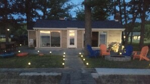 A modern house with a patio area, outdoor seating, and a pathway leading to the entrance.