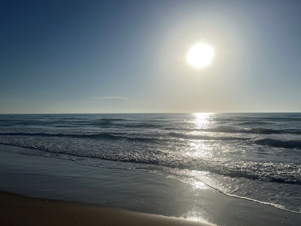 Ein Strand, auf dem sich das Sonnenlicht im Wasser spiegelt.