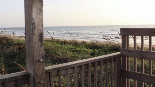 A wooden deck with a railing overlooking a beach.
