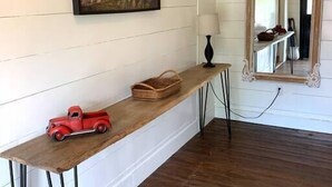 Una consola de madera con un camión de juguete rojo, una cesta tejida y una lámpara.
