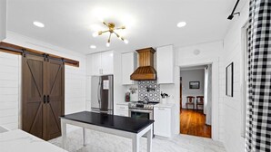 Una cocina moderna con armarios blancos, encimera negra y ventilador de techo de madera.