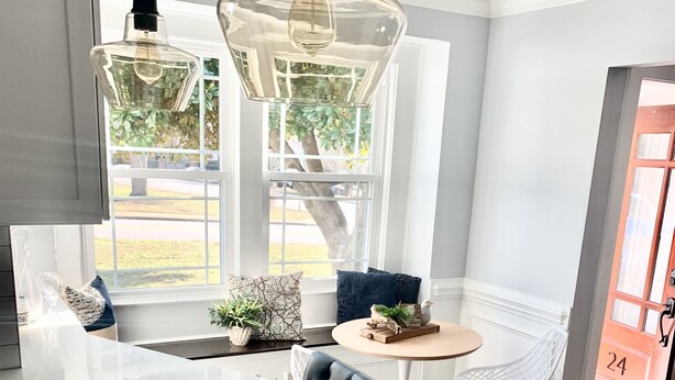 A modern kitchen with a marble countertop, pendant lights, and a view of the outdoors.