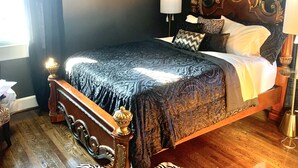 A bedroom with a large bed, a chandelier, a zebra-patterned rug, and a wooden floor.