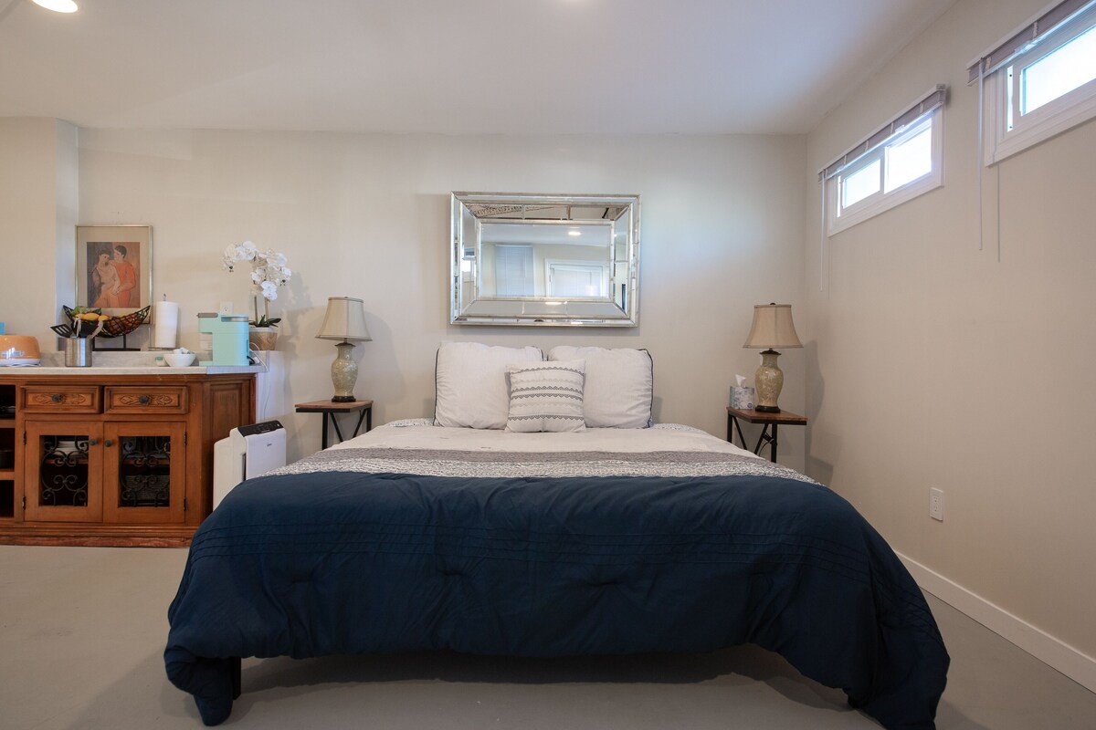 A bedroom with a large bed, a dresser, a mirror, and two bedside tables with lamps.