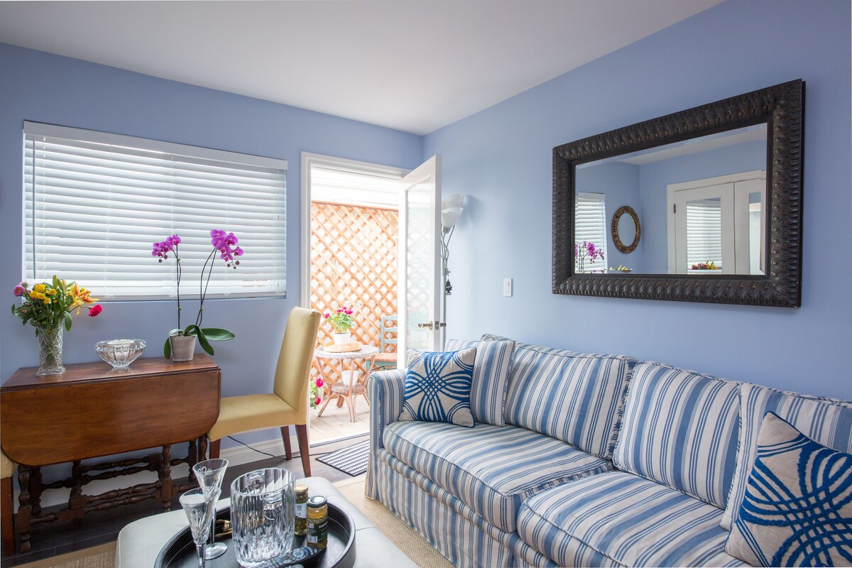 A living room with a striped sofa, a wooden side table, and a vase with flowers.