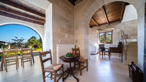 A spacious patio with stone walls, wooden furniture, and a view of the outdoors.
