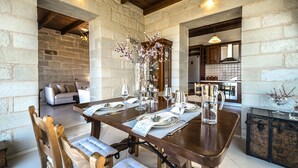 A dining area with a wooden table set for four, surrounded by stone walls and a wooden ceiling.