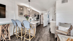 A modern kitchen with white cabinetry, a central island, bar stools, and a dining table.