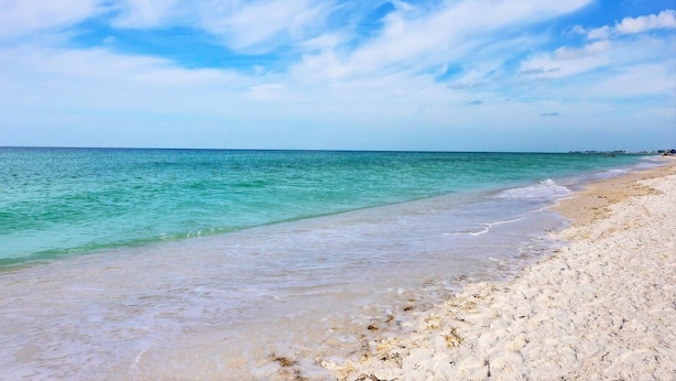 A beach with clear turquoise water and a sandy shore.