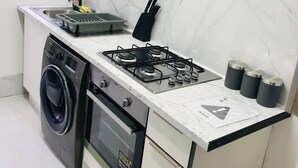 A compact kitchen with a gas stove, a washing machine, and a small sink. - 4 Bedroom Lovely home in Loughborough town & Uni (Loughborough)