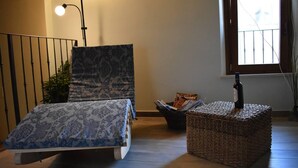 A room with a bed, a small table, a lamp, and a window with a view.