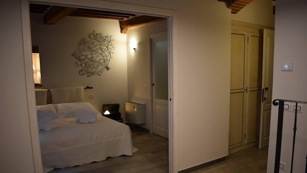 A bedroom with a bed, bedside table, lamp, and a decorative wall piece.