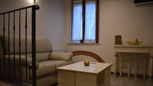 A cozy living room with a sofa, a small table, and a window with curtains.