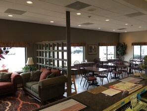 A spacious indoor area with a seating area, a small library, and a counter with informational materials. - Econo Lodge Inn and Suites Shepherd Of The Hills Expy (Branson)