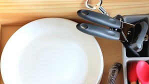 Un cajón de cocina con varios utensilios y vajilla.