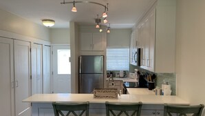A modern kitchen with a central island, white cabinetry, and green chairs. - 7Mile Pool/Seaside Bliss - 2bed 2bath Ground Suite (George Town)