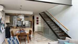 A modern living space with a dining area, kitchen, and a staircase. - Perfect location in Playa! (Playa del Carmen)